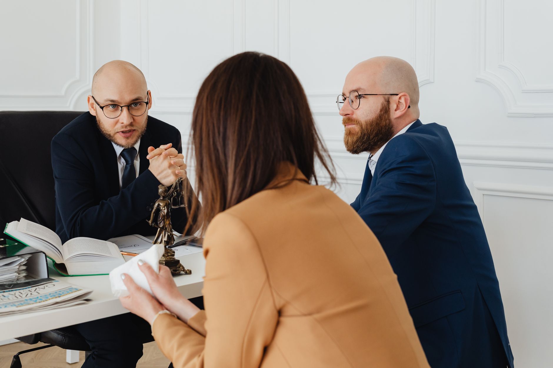 Advogados conversando com uma cliente em uma mesa de reunião